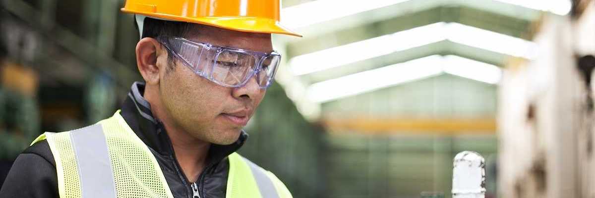 Factory worker writing on a clipboard while checking work