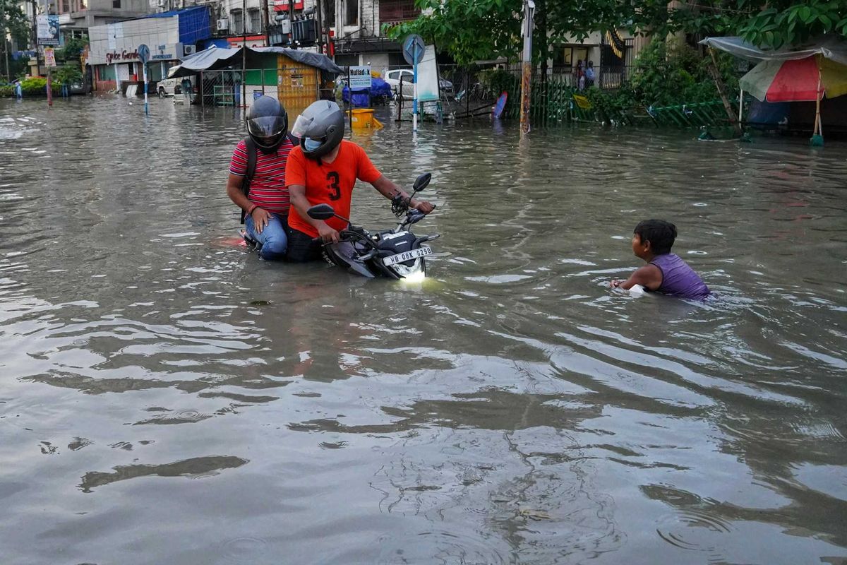 Filipinos navigating flooded street on motorcycle