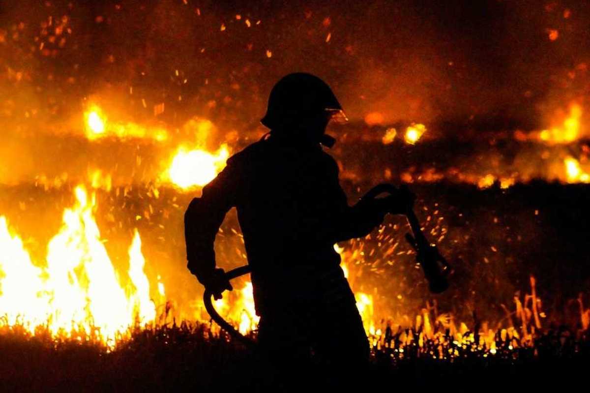 Firefighter silhouetted against flames at night