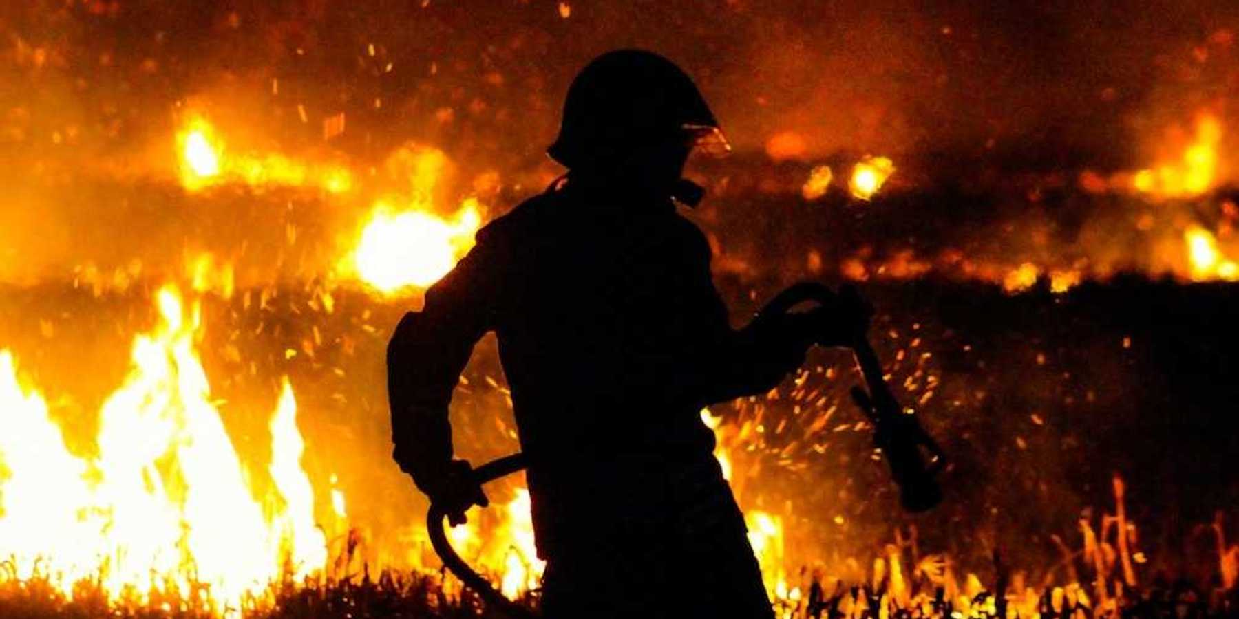 Firefighter silhouetted against flames at night