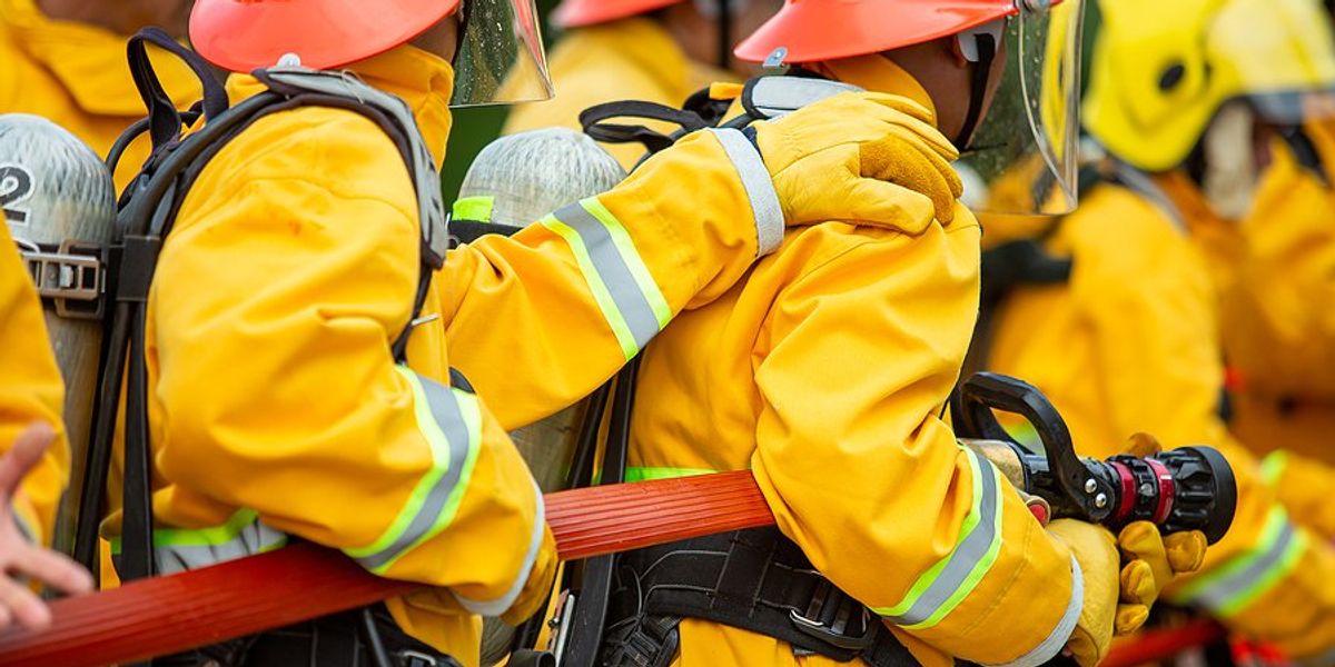 Firefighters holding red fire hose