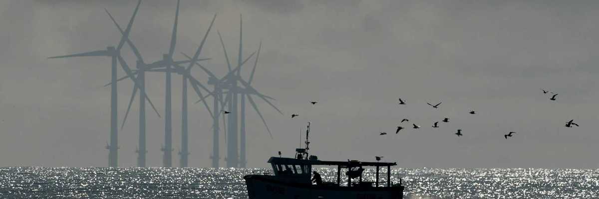 Fishing boat with offshore wind turbines in background