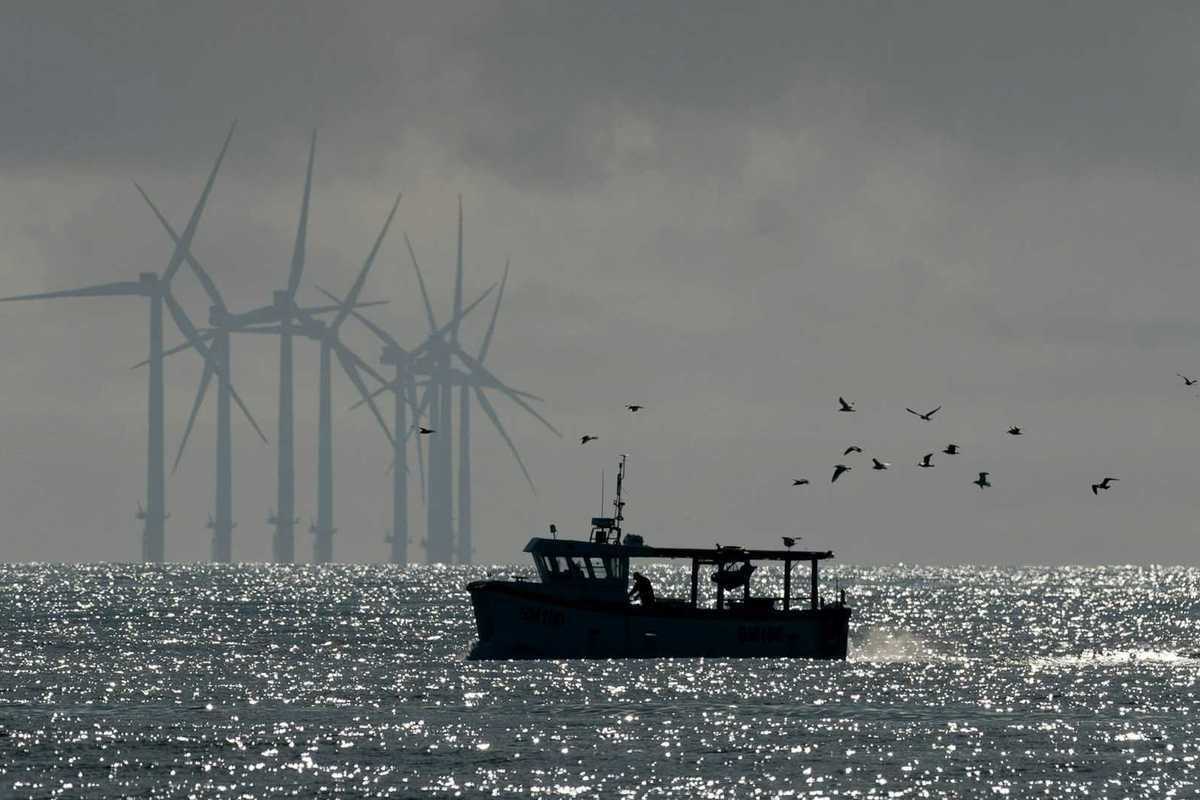 Fishing boat with offshore wind turbines in background