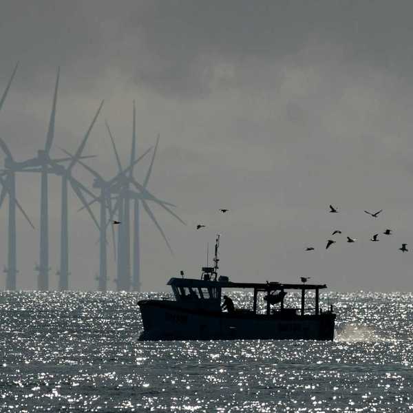 Fishing boat with offshore wind turbines in background
