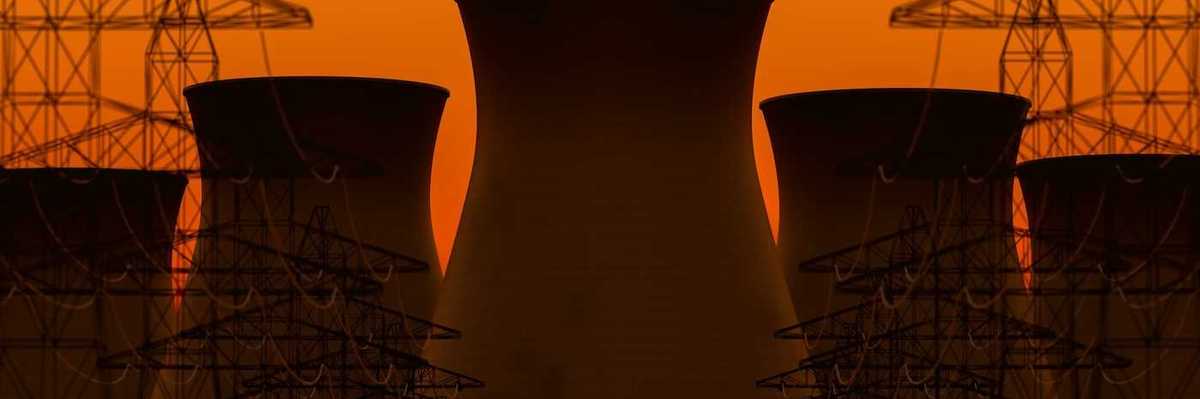 Five nuclear power plant cooling towers sillhouetted against transmission lines and orange sky