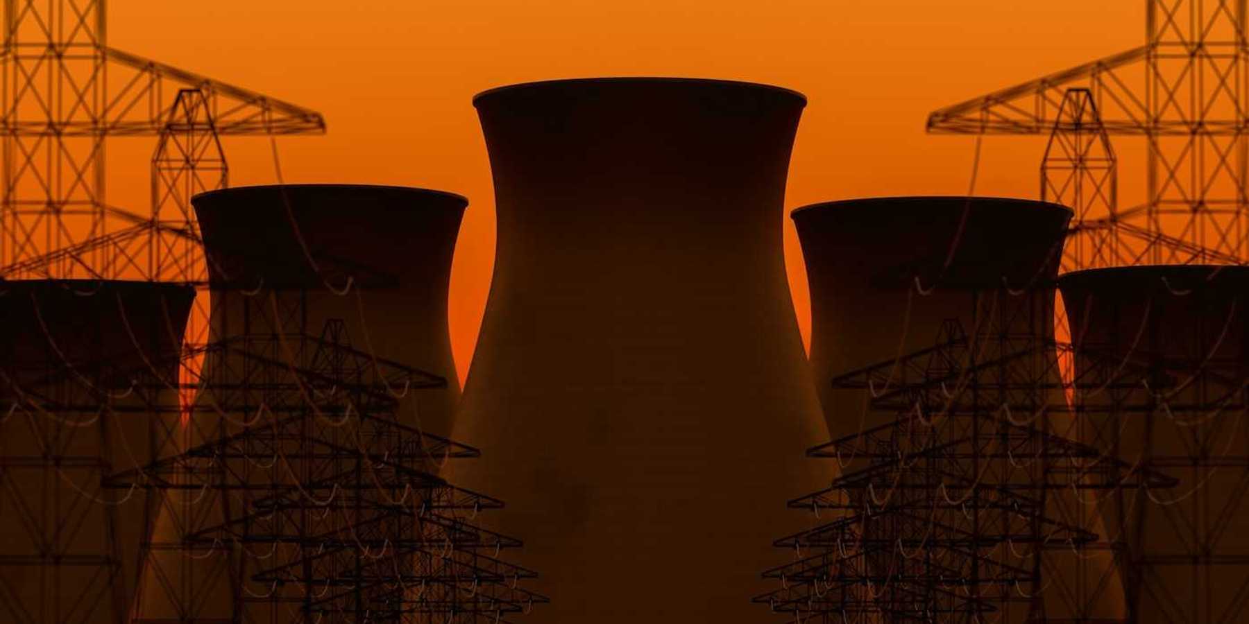 Five nuclear power plant cooling towers sillhouetted against transmission lines and orange sky