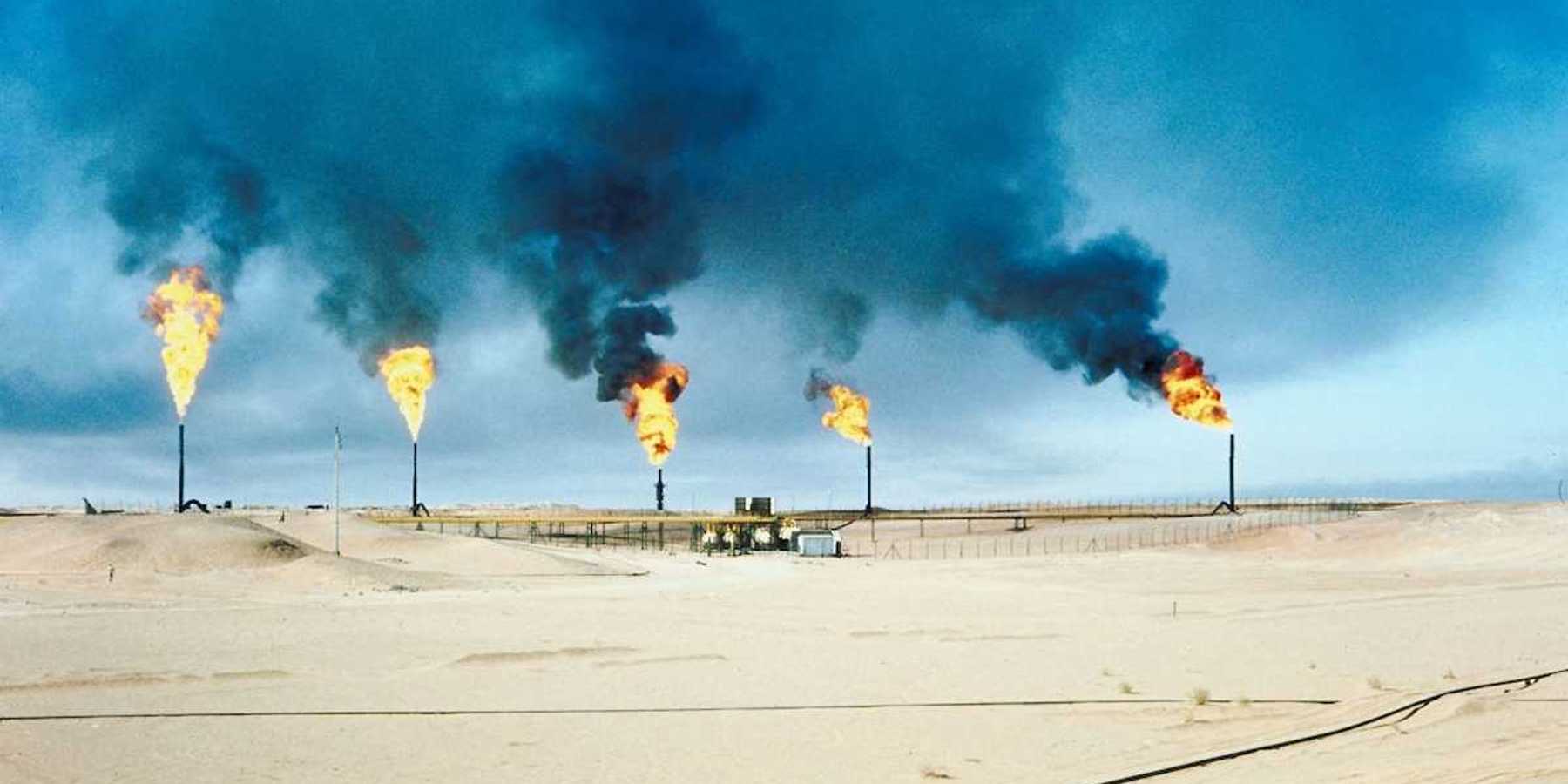 Five oil and gas wells burning off methane in a desert (Middle East?) environment.