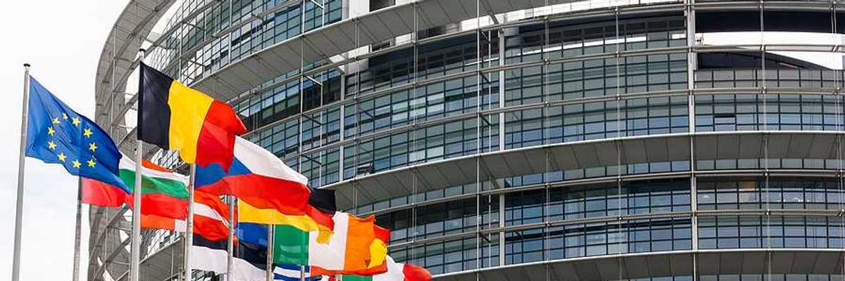 Flags of the EU flying outside a glass and steel building