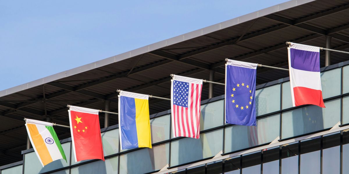 Flags of various nations fly on building.