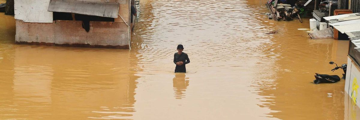 Flooding engulfs homes and a person stands in the water.