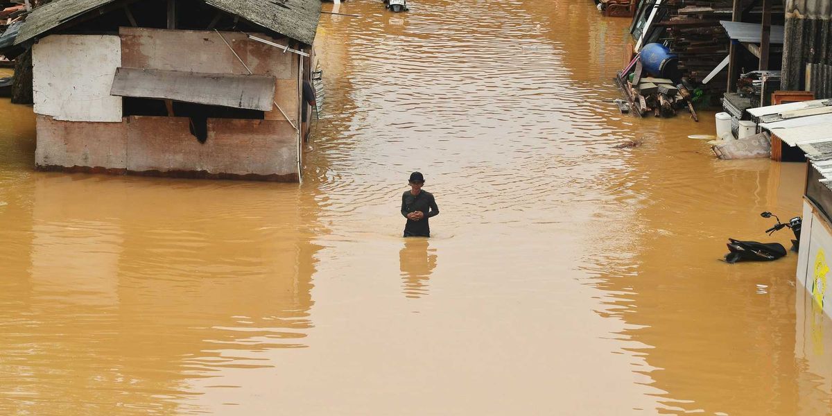 Flooding engulfs homes and a person stands in the water.