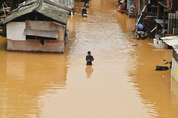 Flooding engulfs homes and a person stands in the water.