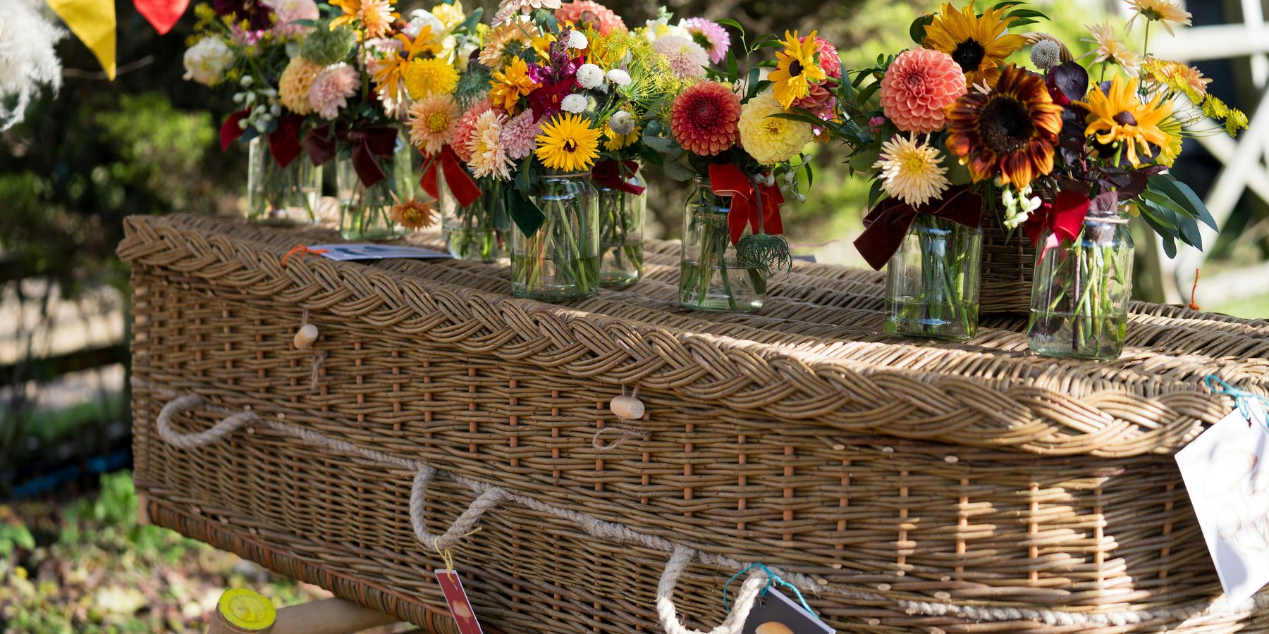 Flowers adorn a wicker coffin at a celebration of life.