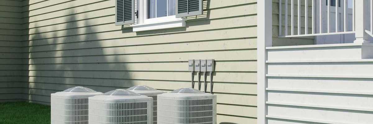 Four air conditioning units positioned next to a residential structure