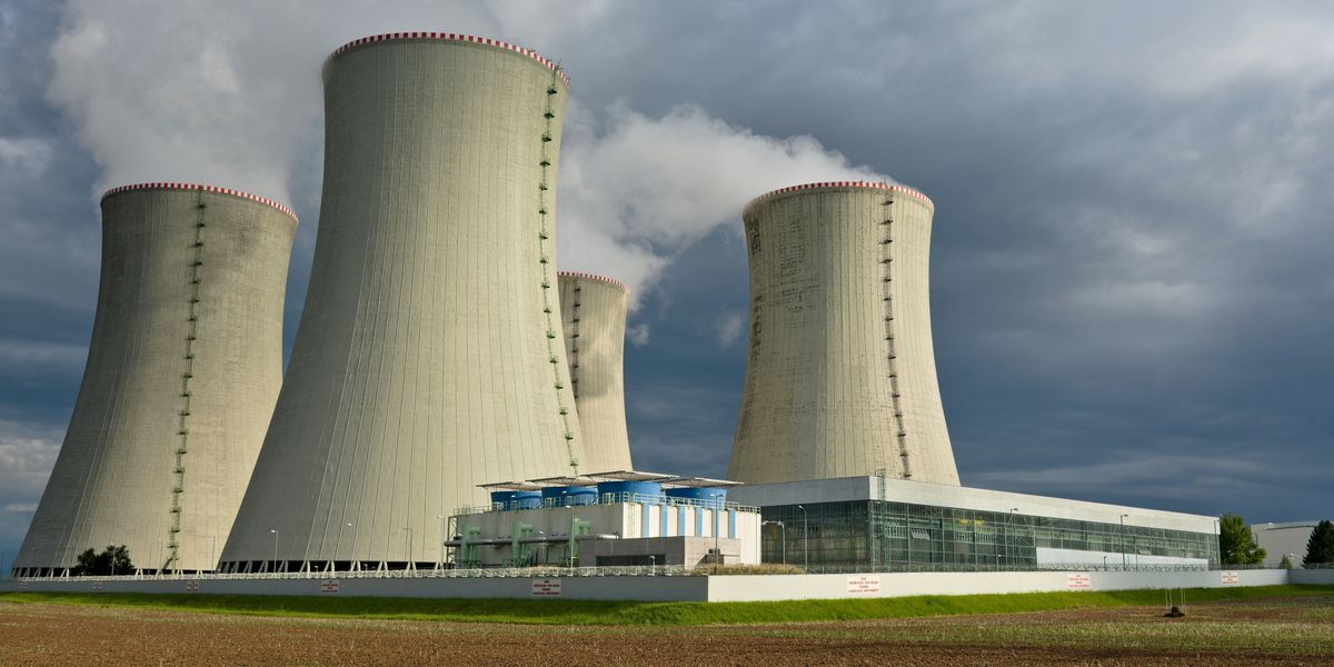 Four nuclear towers in a power plant with cloudy skies in background.