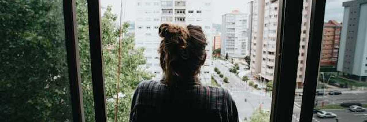 Girl looking out of her window in the city