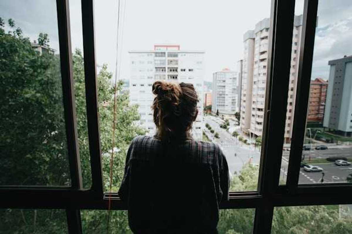 Girl looking out of her window in the city