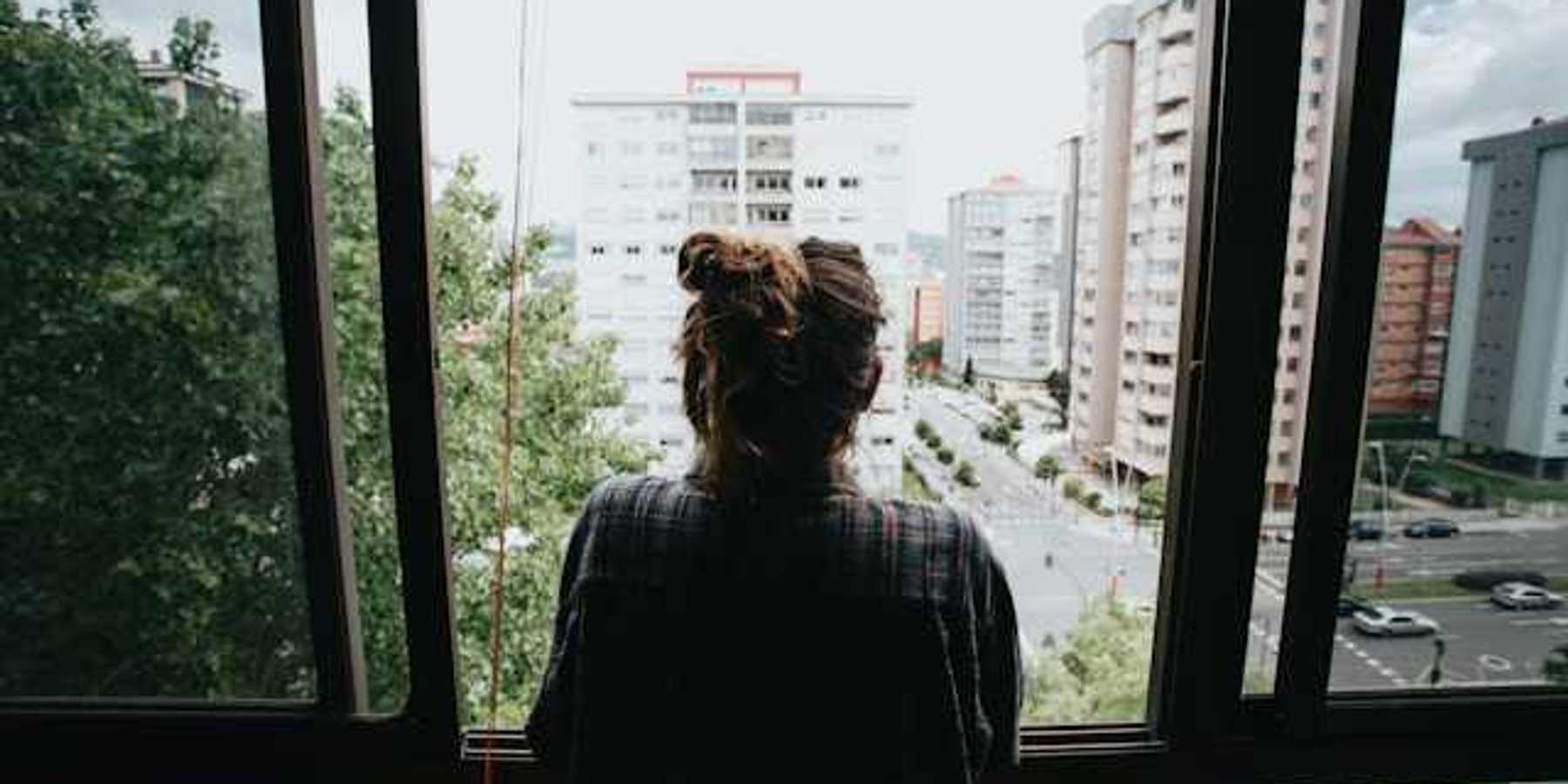 Girl looking out of her window in the city