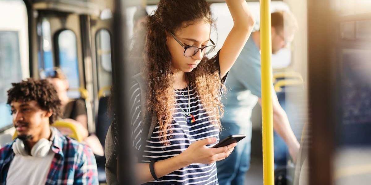 Girl riding bus while standing and checking cell phone