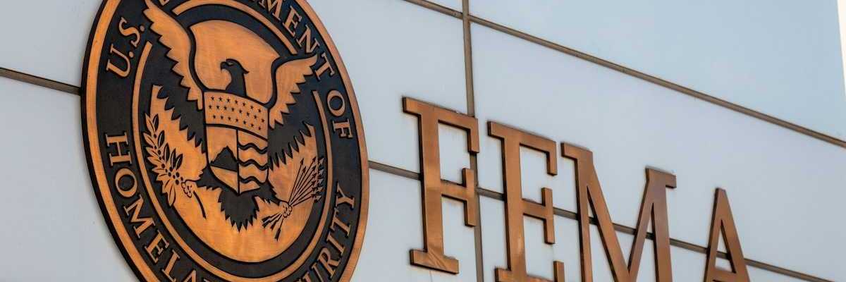 Gold-colored FEMA sign on building adjacent to Department of Homeland Security logo
