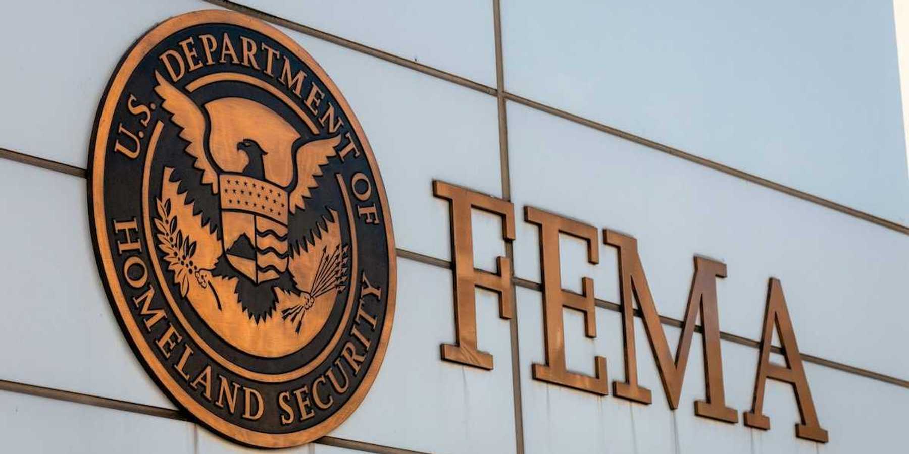 Gold-colored FEMA sign on building adjacent to Department of Homeland Security logo