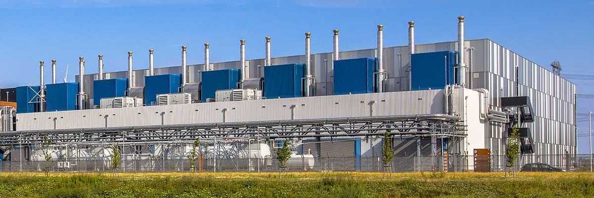 Google Datacenter adjacent to a waterway near Delfzijl in the province of Groningen, Netherlands, under blue sky.