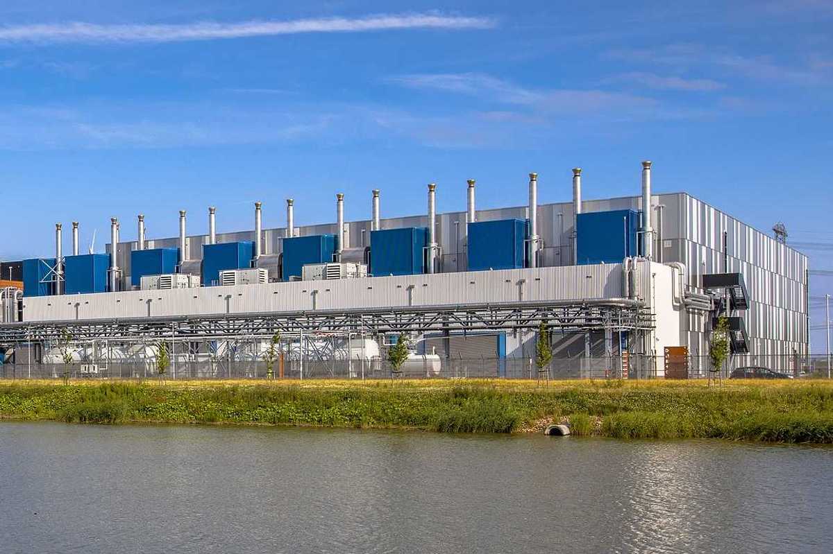 Google Datacenter adjacent to a waterway near Delfzijl in the province of Groningen, Netherlands, under blue sky.