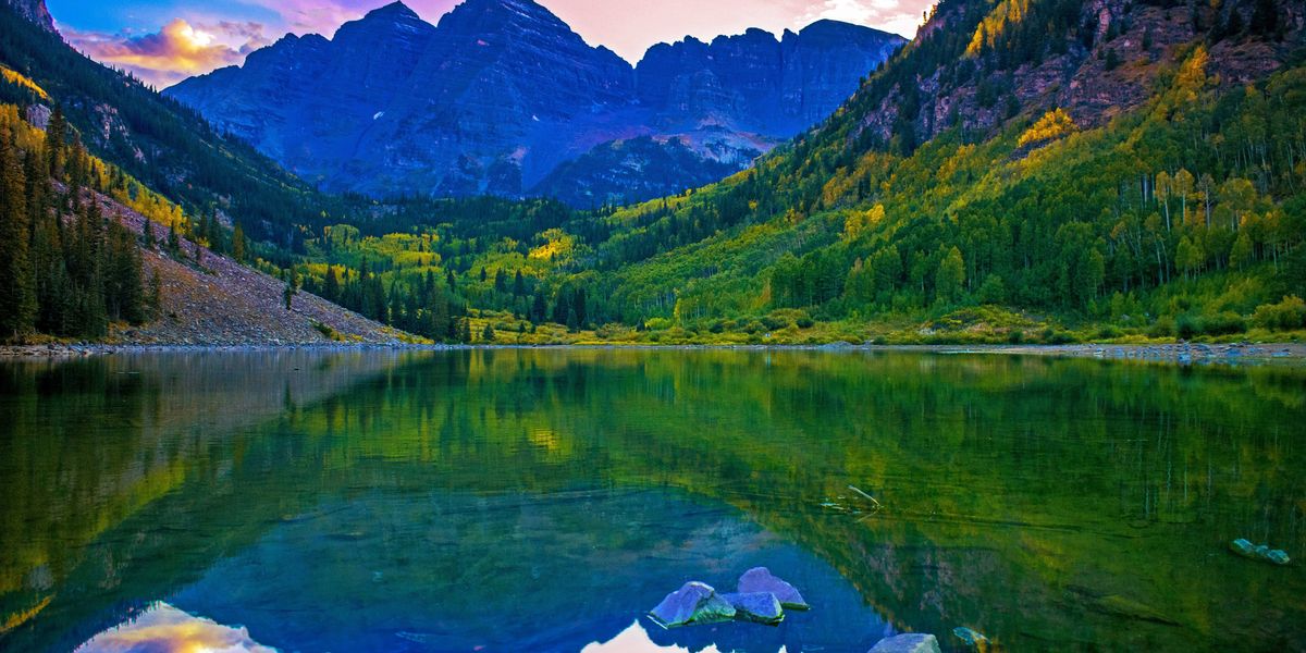 green trees and mountains near lake during daytime