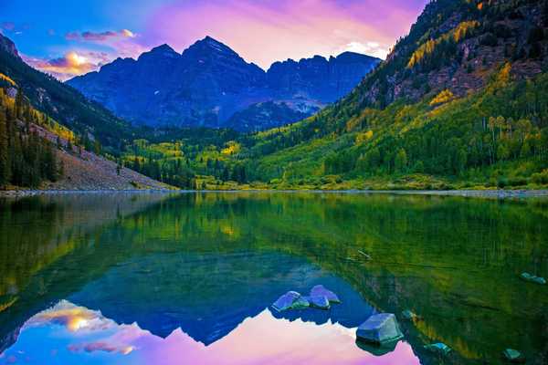 green trees and mountains near lake during daytime