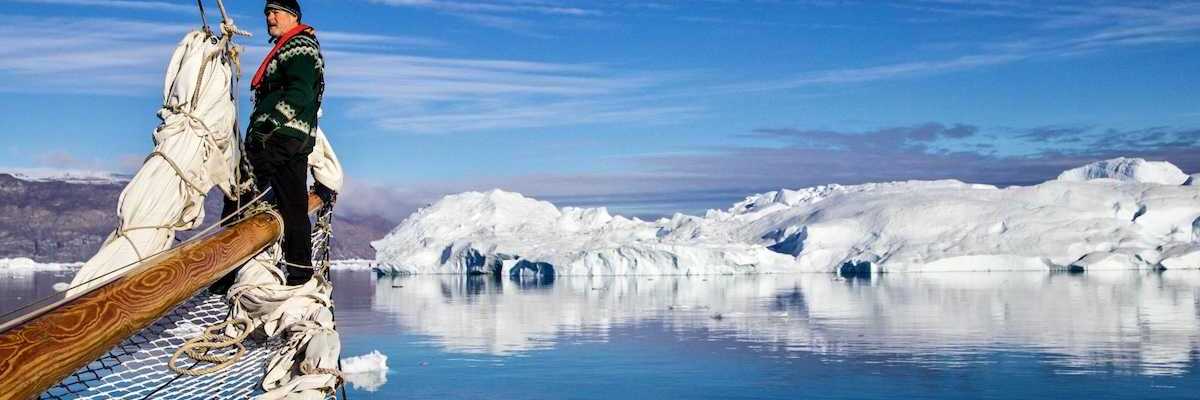 Greenland fisherman on his boat with ice floes in background