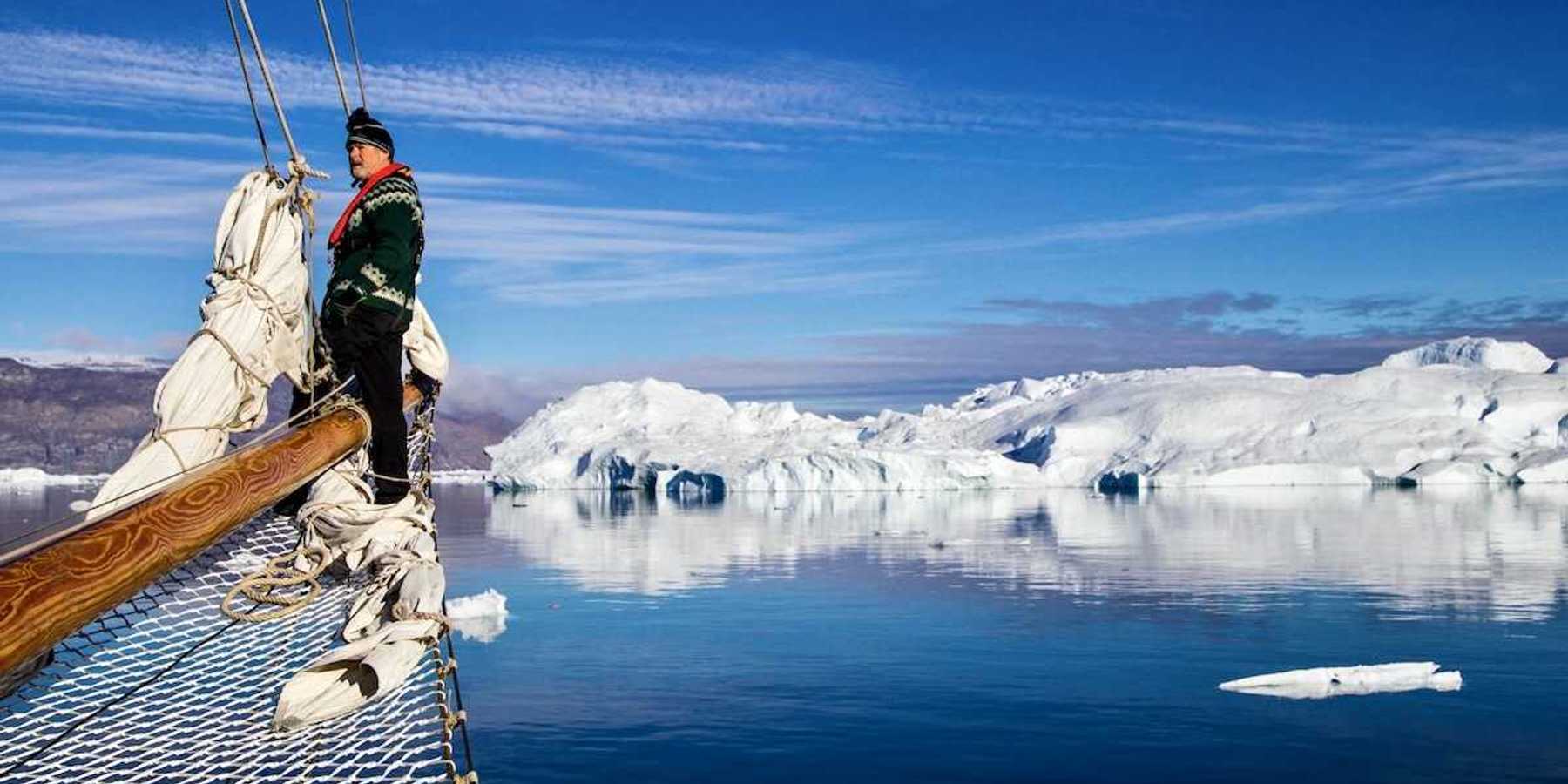Greenland fisherman on his boat with ice floes in background