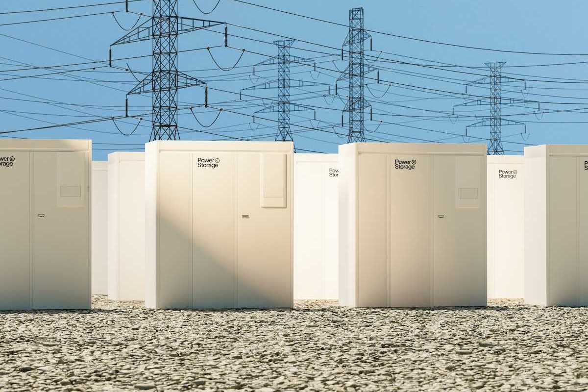 Grid-scale batteries aligned in rows with transmission lines behind