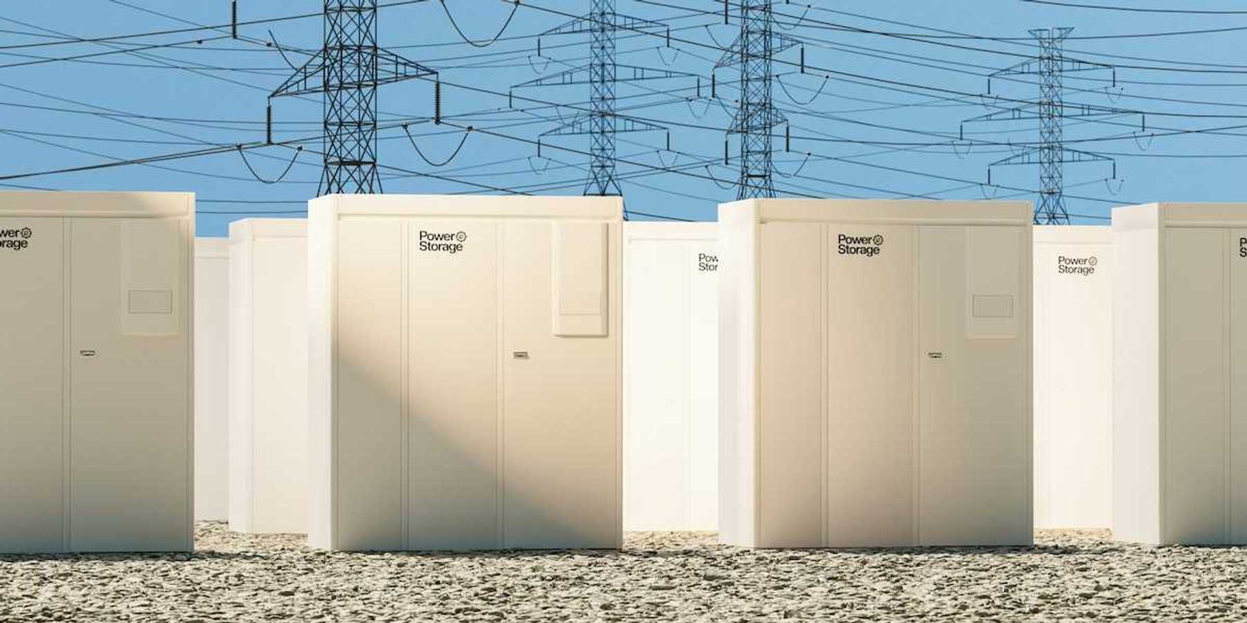 Grid-scale batteries aligned in rows with transmission lines behind