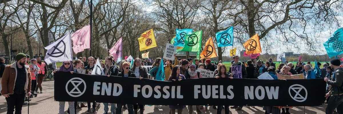 Group of activists marching , holding a banner that reads "END FOSSIL FUELS NOW."