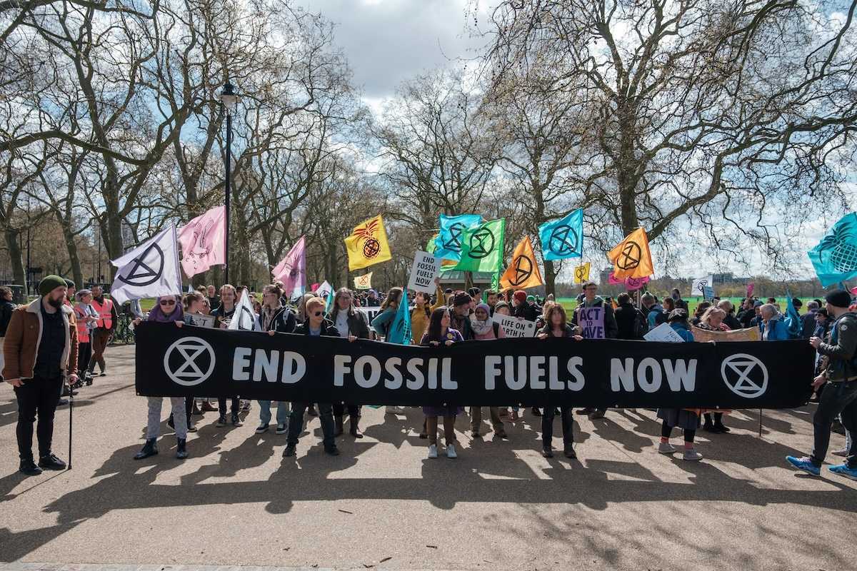 Group of activists marching , holding a banner that reads "END FOSSIL FUELS NOW."
