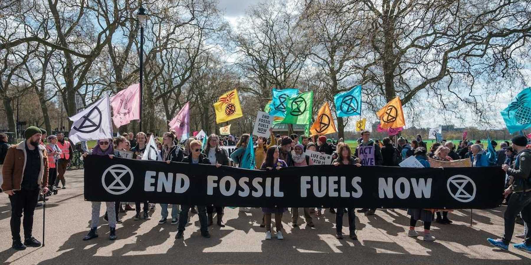 Group of activists marching , holding a banner that reads "END FOSSIL FUELS NOW."