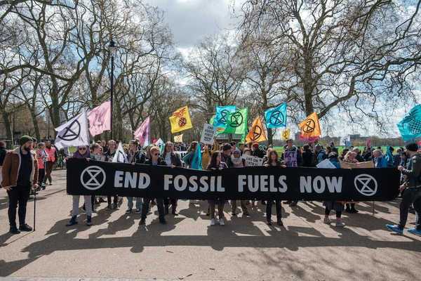 Group of activists marching , holding a banner that reads "END FOSSIL FUELS NOW."