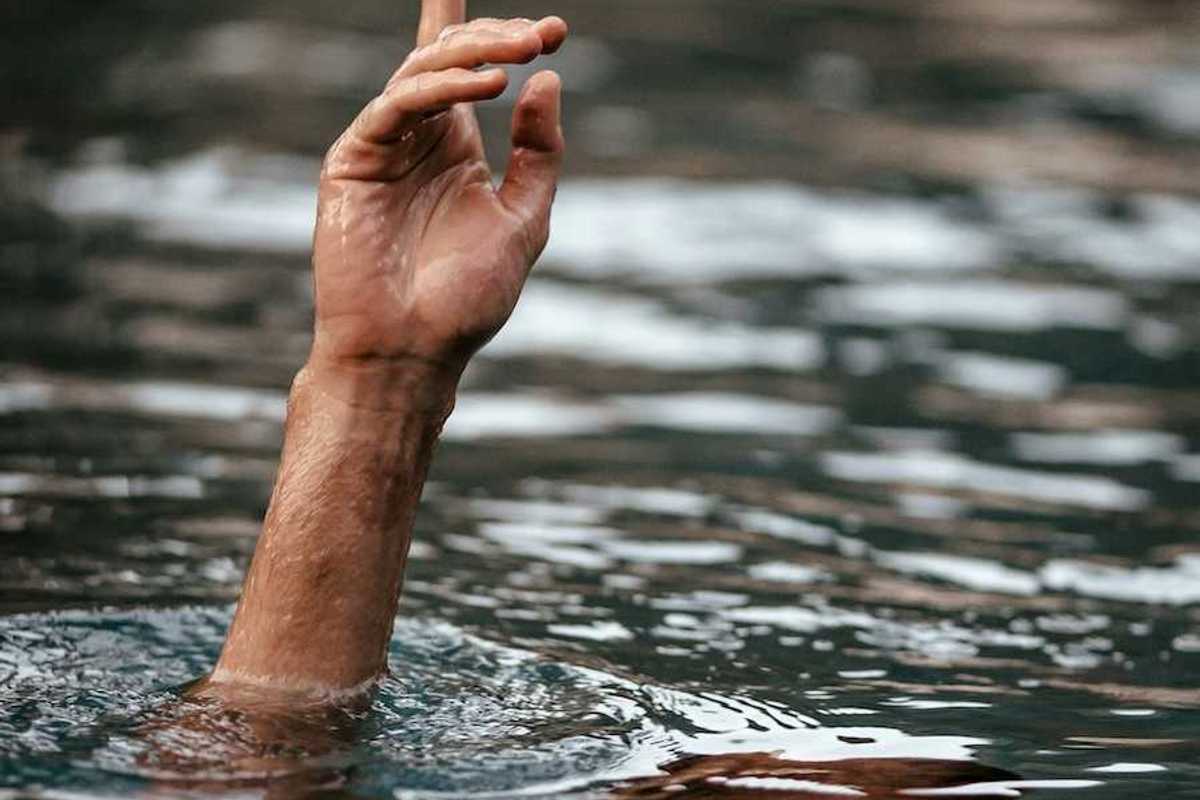Hand and partially submerged forearm sticking out of floodwaters, one finger pointing up