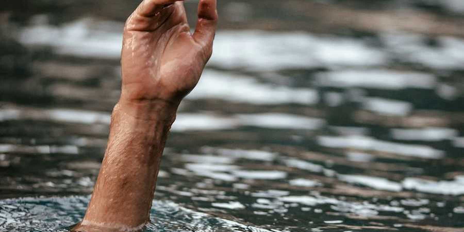 Hand and partially submerged forearm sticking out of floodwaters, one finger pointing up