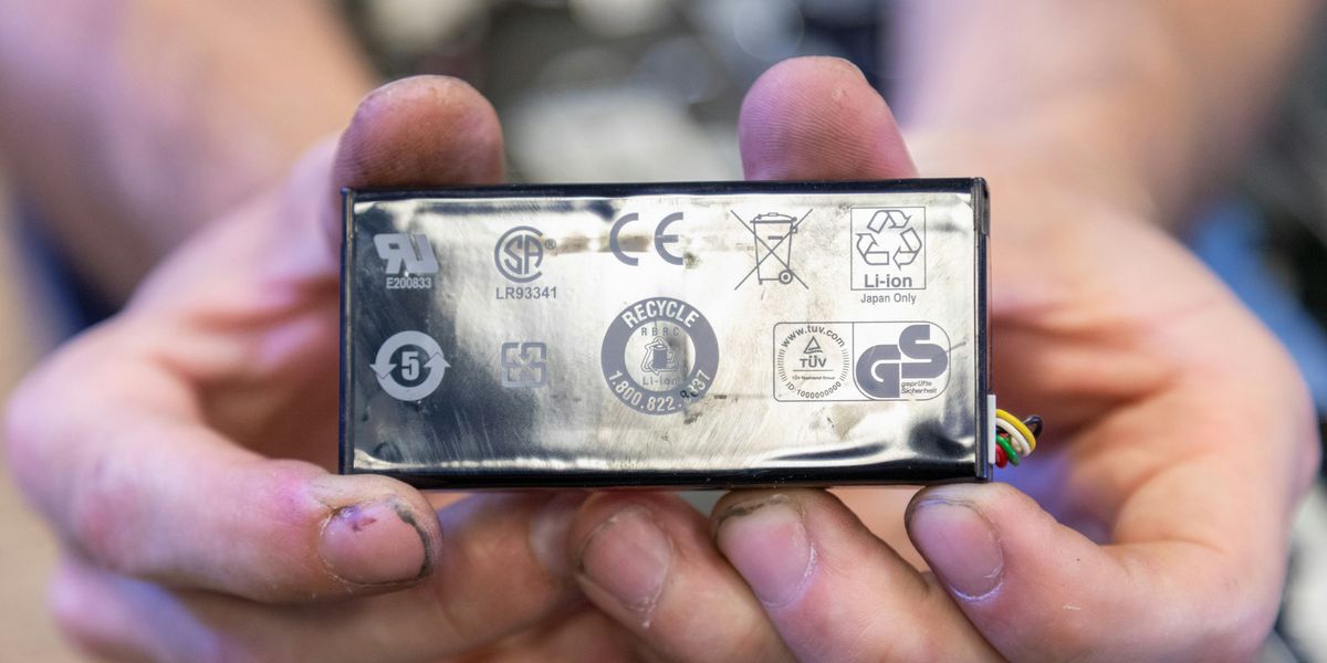Hands hold an electronic device with various icons and logos including a recyclig logo.