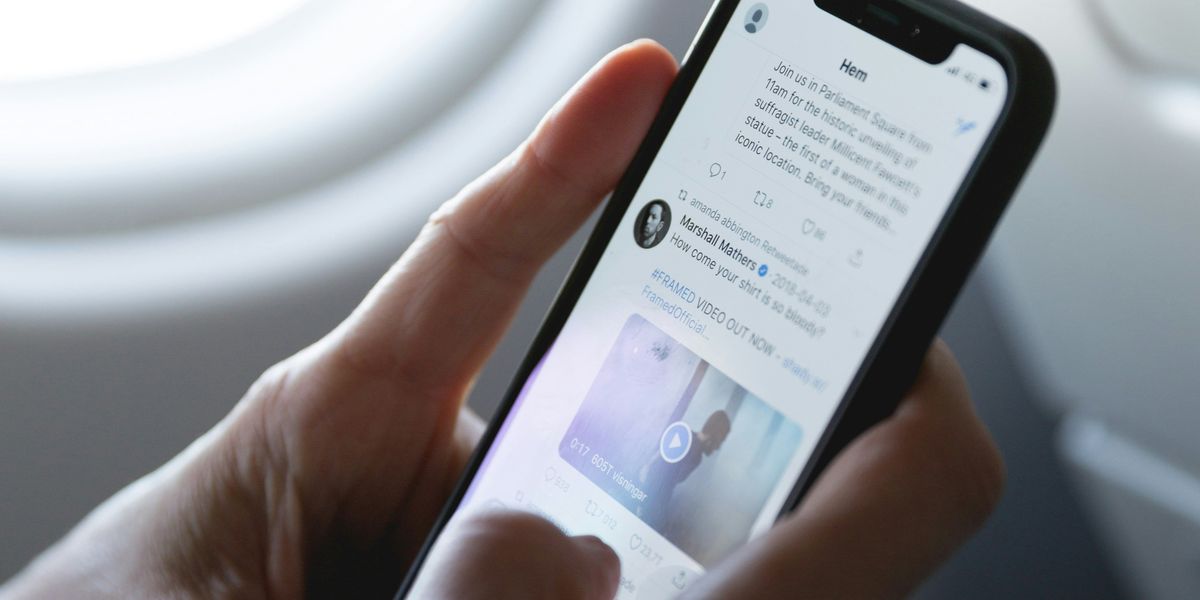 hands holding a cell phone, scrolling Twitter