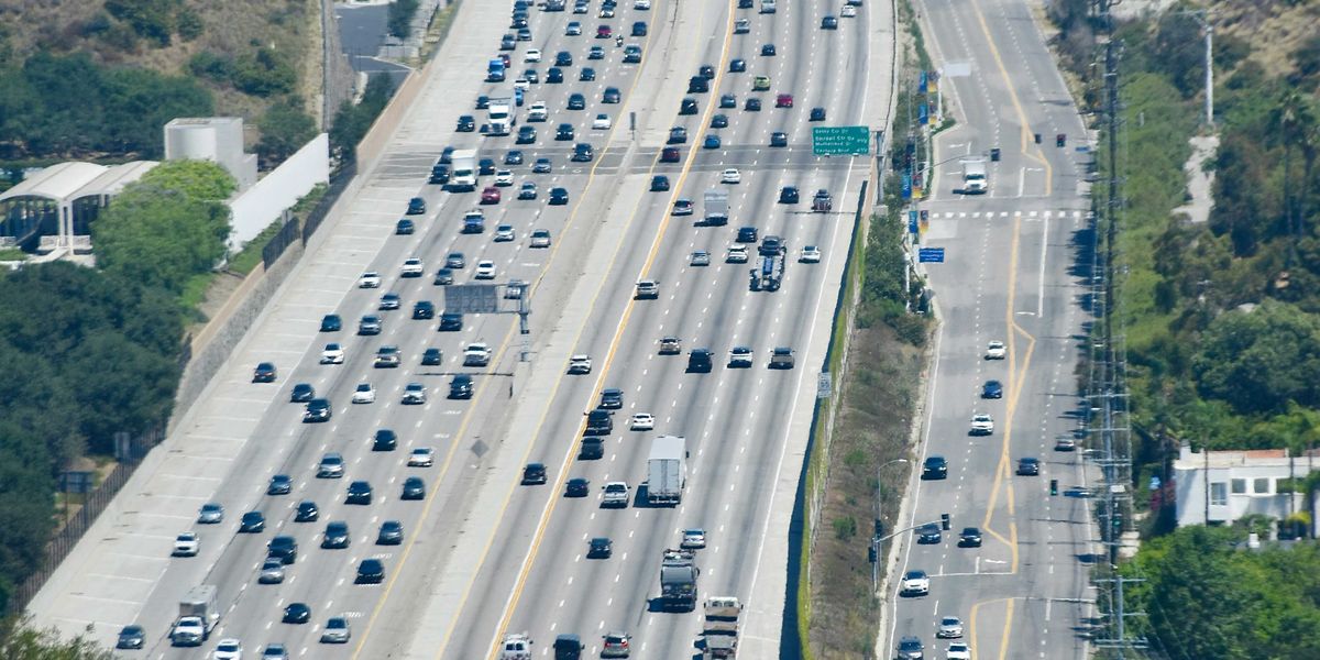Heavy traffic on a multi-lane highway through hills.