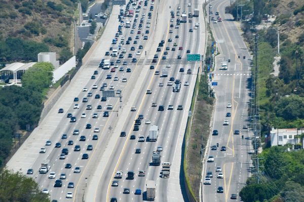 Heavy traffic on a multi-lane highway through hills.