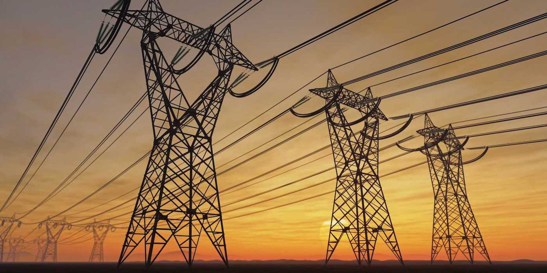 High voltage transmission towers against a setting or rising sun