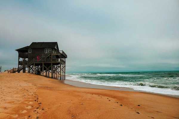 House on stilts precariously positioned next to ocean in Rodanthe, North Carolina