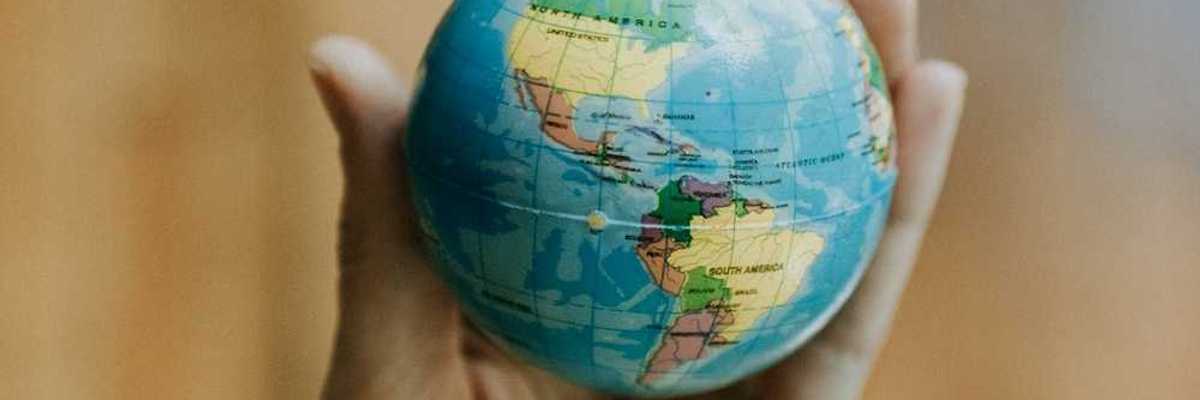 Human hand holding a miniature globe showing both North and South America