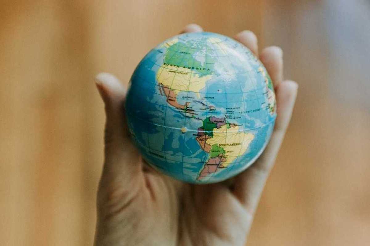 Human hand holding a miniature globe showing both North and South America
