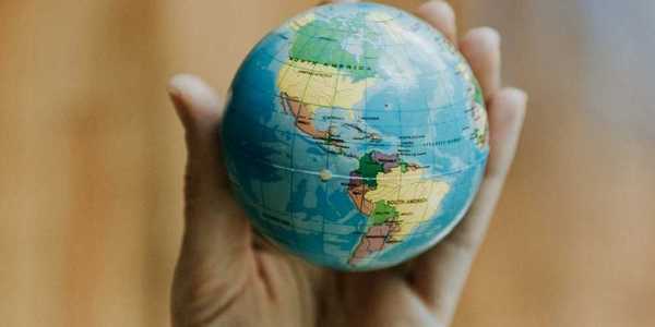 Human hand holding a miniature globe showing both North and South America