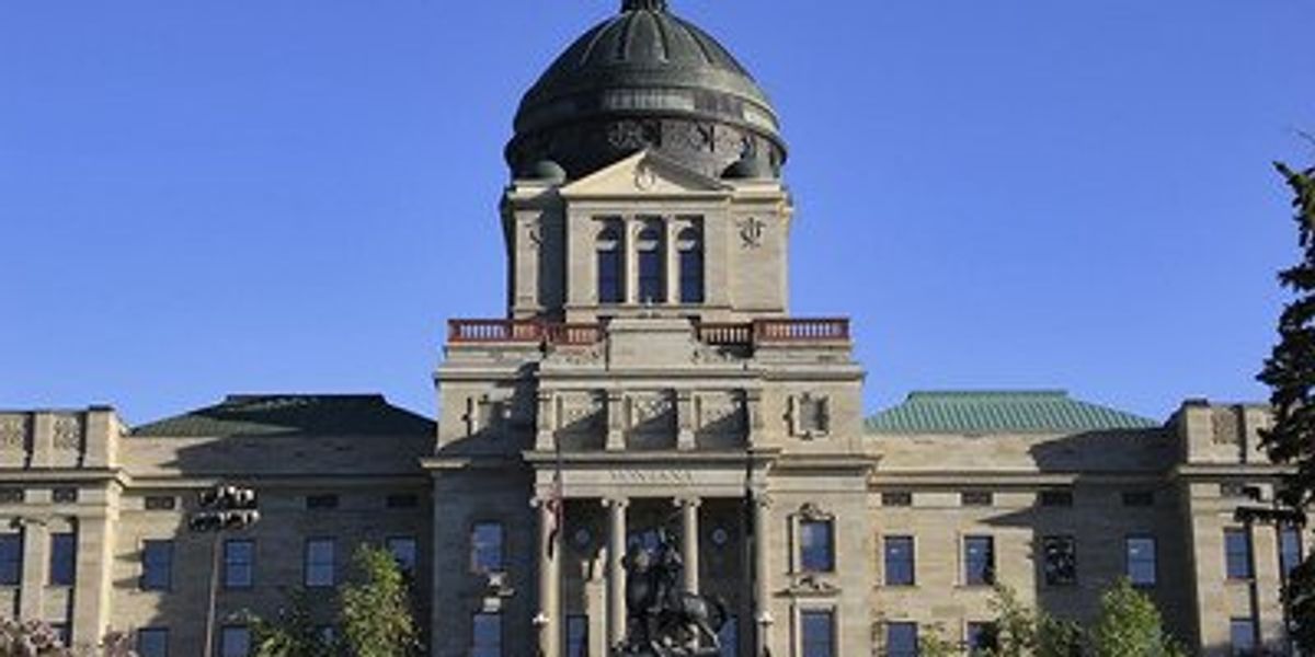Image of a state capitol building during daytime with a statue in the front.