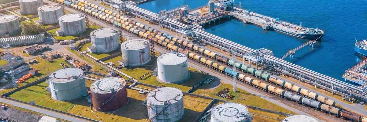 Import/export shipping terminal intersected by a rail line stacked with railroad tanker cars for liquid transport